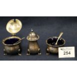 Three piece silver baluster shaped condiment set with blue glass liners and two silver spoons.