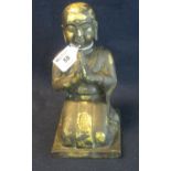 A heavy probably bronze figure of the Buddha kneeling at prayer. Traces of gilded decoration and