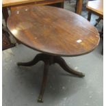 19th Century mahogany oval centre table on quatreform reeded base with brass paw mounts and casters.