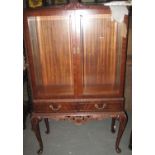 Mid Century mahogany two door display cabinet on projecting base with two drawers and carved