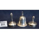 Three silver items to include; two jar covers with long handles and a bell shaped loaded silver