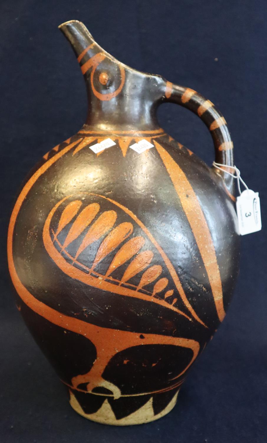 An unusual Art pottery single handled jug of baluster form on a brown and orange ground in the