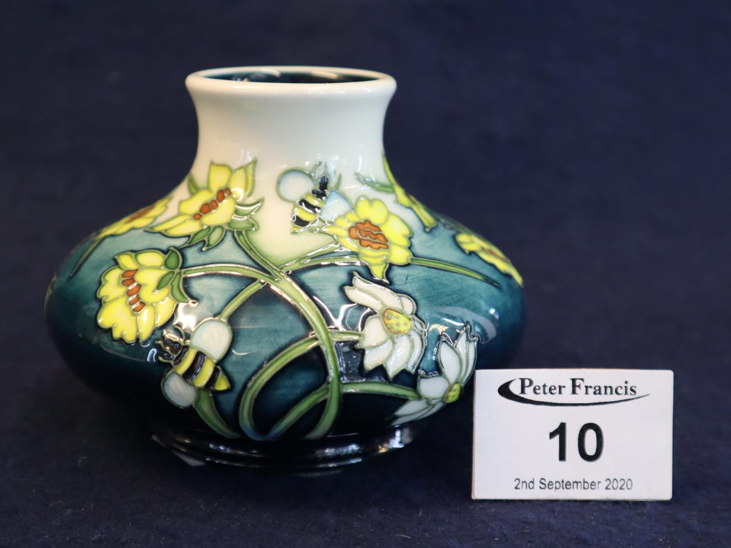 A Moorcroft art pottery tube lined vase of squat form decorated with bees, flowers and foliage,