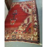 Middle Eastern design hand woven rug on a red ground with stylised flower heads and similar