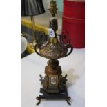 A classical design yellow metal urn shaped table lamp with painted porcelain figural panels on a