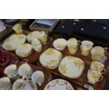 Two trays of Royal Albert bone china part teaset on a yellow ground with yellow flowers and foliage.