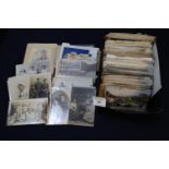 Postcards in black box of military interest, including soldiers, battle scenes, bomb damage, comic