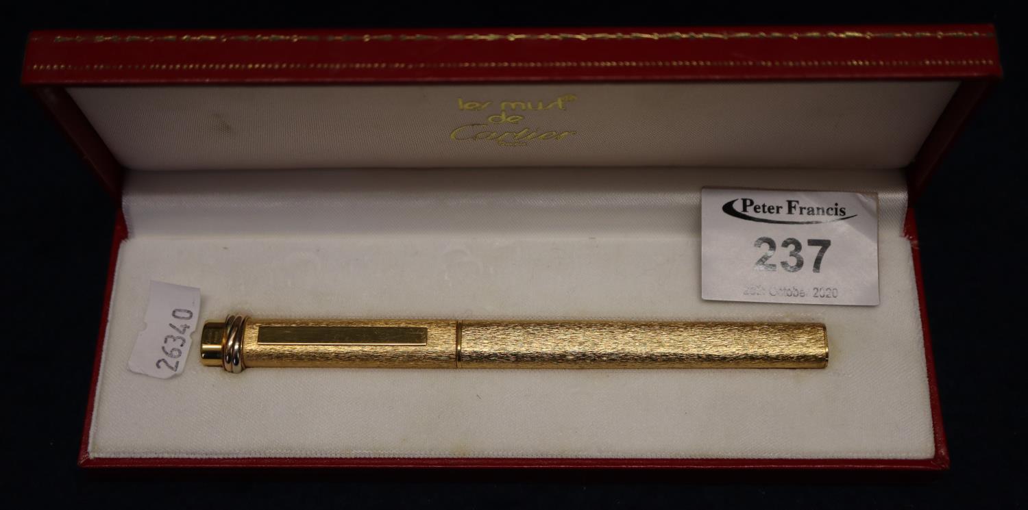 A Cartier of Paris gold plated ball point pen with bark finish in red leather original Cartier