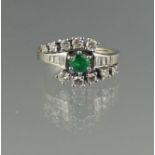 14CT WHITE GOLD EMERALD AND DIAMOND CROSS OVER RING. The central emerald estimated 4mm, surrounded