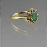 18CT GOLD EMERALD AND DIAMOND CLUSTER RING. The oval deep green claw set emerald (8 x 6mm approx)