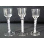 THREE SIMILAR GEORGIAN OPAQUE MULTIPLE TWIST STEM ALE GLASSES with circular feet, two with