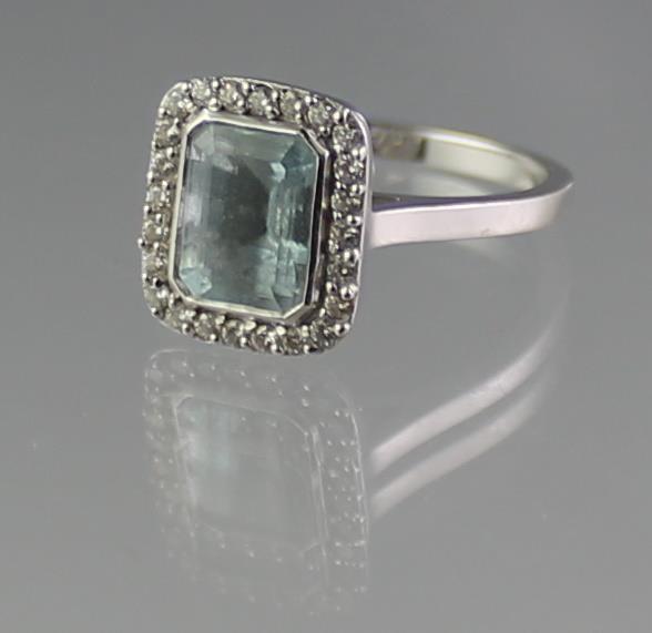 18CT WHITE GOLD AQUAMARINE AND DIAMOND RING. The step cut aquamarine surrounded by diamonds. Ring