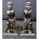 AN UNUSUAL PAIR OF CARVED EBONISED WOODEN FIGURES of kneeling slaves supporting match holders or
