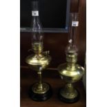 Two similar brass oil lamps with brass reservoirs and brass pedestals on ceramic bases with clear