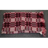 A vintage red ground Welsh tapestry blanket with fringed edging with a 'Made in Mid Wales' label