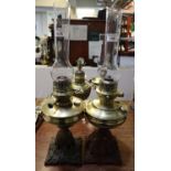 Two similar brass oil lamps with cast iron pierced bases and clear chimneys. (2) (B.P. 21% + VAT)