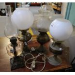 A group of four brass oil lamps with shades, one converted to electricity. (4) (B.P. 21% + VAT)