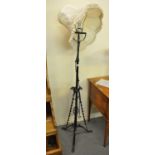 Wrought iron standard lamp with shade, having swirl and scrolled foliate decoration on tripod