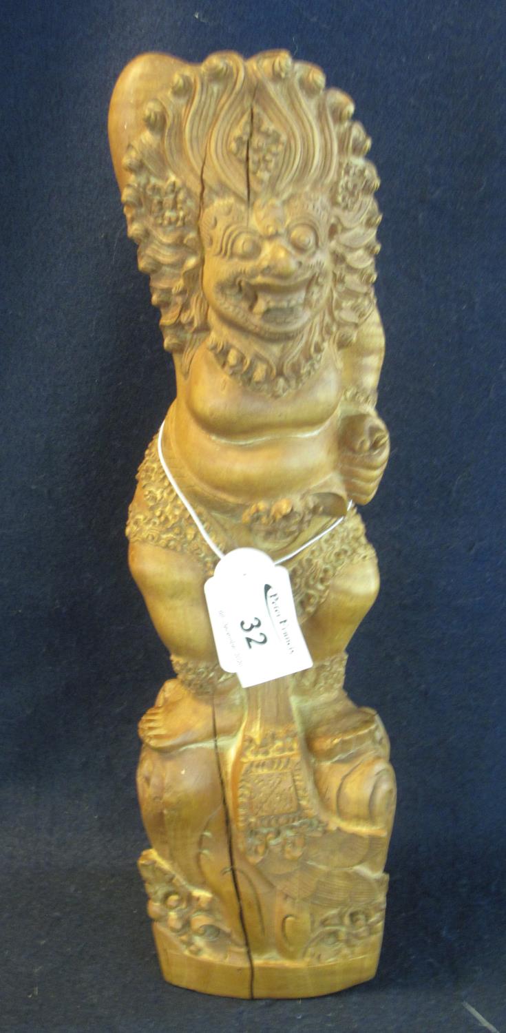 A Balinese carved wooden figure of a deity in dancing form with lion mask head dress on naturalistic