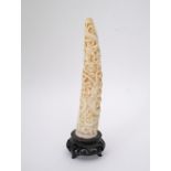 An antique Chinese carved ivory tusk with dragons amongst clouds on wooden base, H18cm including