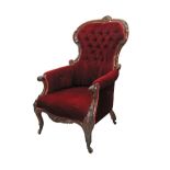 A Victorian carved walnut spoonback armchair in red velvet upholstery, on castors. W63cm.