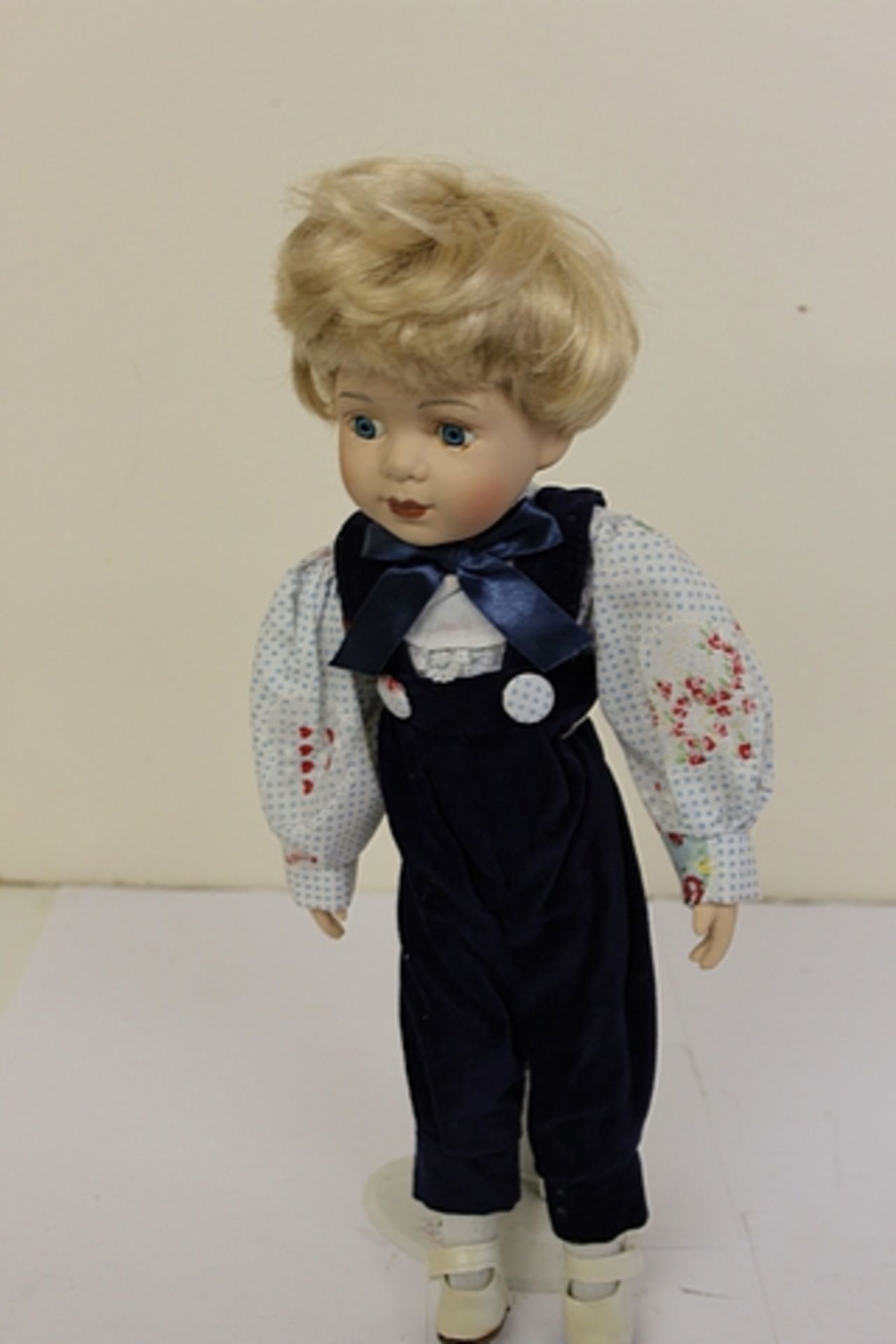 Porcelain Doll Wearing A Pair Of Velvet Dungarees With A Pretty Blouse