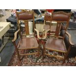 A pair of period oak elbow hall chairs with leather stud seat pad open carve back splat and