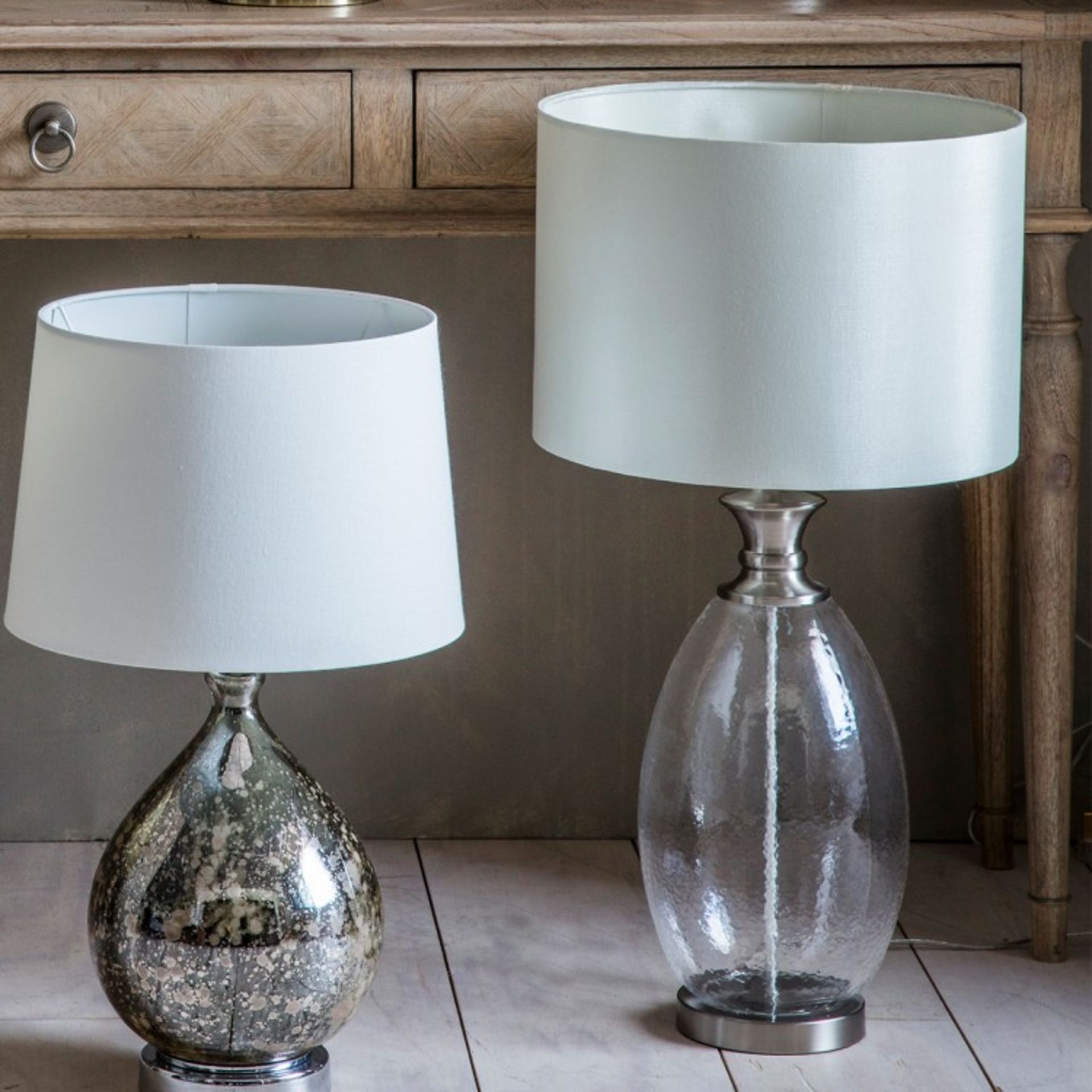Sulgrave Table Lamp With a clear glass base and a white cylindrical shade, the Sulgrave table lamp