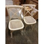 A pack of 2 understated cross back chairs in a distressed white wood finish with canvas seat pads.