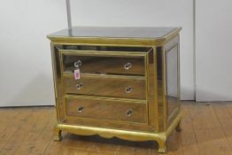 A decorative mirrored chest of drawers, set throughout with bevelled distressed plates within gilt