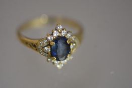 A sapphire and diamond cluster ring, the oval-cut sapphire claw-set within an arrangement of