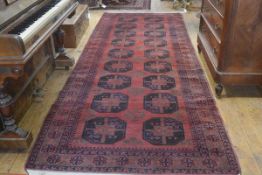 An Afghan Bokhara hall rug, finely knotted, the centre panel with twin rows of nine octagons