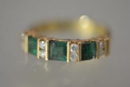 An emerald and diamond dress ring, the three cushion-cut emeralds spaced by pairs of round