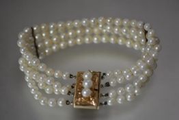 A 14ct gold and cultured pearl four strand bracelet, the uniform strands with a pair of gold spacers