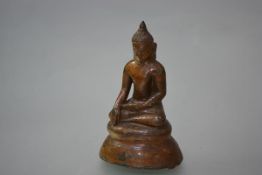 A gilt/brown patinated metal figure of a seated Buddha, possibly South-East Asian, with clay core.