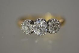 A three stone diamond ring, early 20th century, the graduated brilliant cut stones in coronet collet