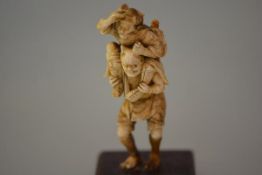 A Japanese marine ivory okimono of an Oni, a Samurai on his back clutching a horn, Meiji period,