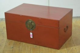 A Chinese red lacquer trunk, of plain rectangular form, fitted with characteristic circular lock