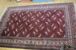 A Bokhara rug with central red panel, with repeat geometric medallions, flanked by multiple borders,