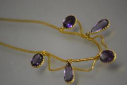 A striking Victorian amethyst fringe necklace, the yellow metal snakelink chain suspending three