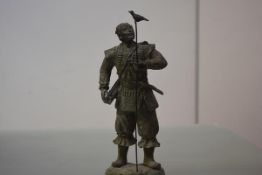 A large Oriental patinated metal figure of a warrior, probably Japanese, modelled in armour,