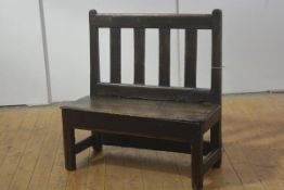 A 19th century elm country bench, with plain slatted back over a plank seat, raised on square