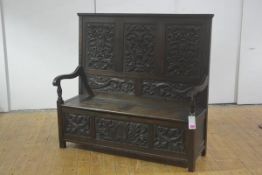 A carved oak box settle in 18th century style, 19th century, the high three panel back carved in