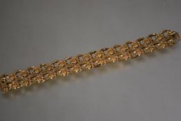 An 18ct gold fancy link bracelet, with twin bands of floral-cast panels between shaped links,