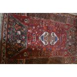 A Persian carpet, the central red field with two geometric urns, flowerhead decoration, flanked by