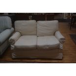 An upholstered two seater sofa with cream loose covers