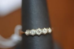 A five stone set diamond ring on yellow metal band, marked 18ct