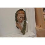 A vintage wall plaque of a woman's head in scarf in painted plaster
