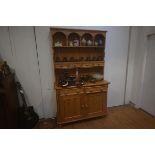 A 19thc two part pine kitchen dresser, the moulded top with arched gallery, a row of four spice