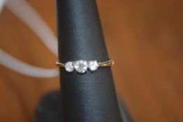 A three stone diamond ring on white metal band